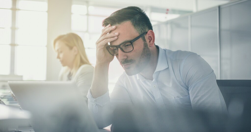 Mann schaut angestrengt auf den Bildschirm seines Laptops